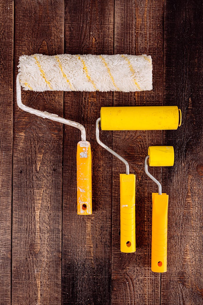 Top view of yellow paint rollers arranged on a wooden table for DIY projects.